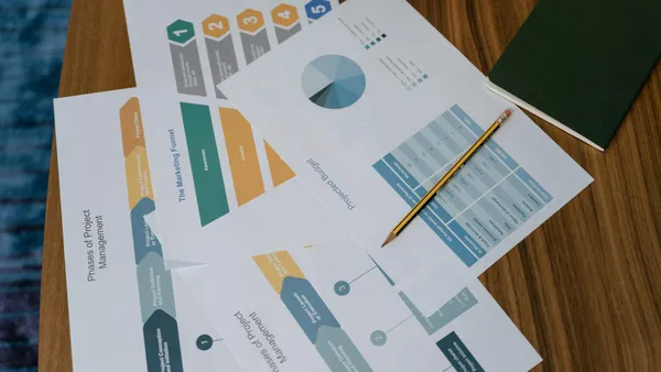 Vue aérienne de documents de gestion de projet et de graphiques sur un bureau avec un crayon