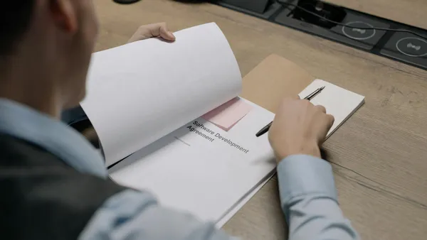 Professionnel analysant des options de logiciel de gestion commerciale à son bureau