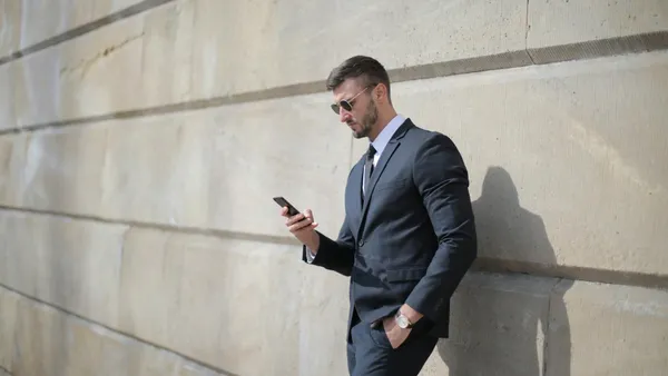 Comercial consultando datos de clientes en su teléfono móvil mientras está fuera de la oficina