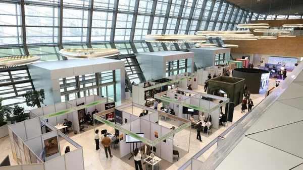 Salon professionnel animé dans un hall moderne avec des professionnels qui réseautent et visitent les stands