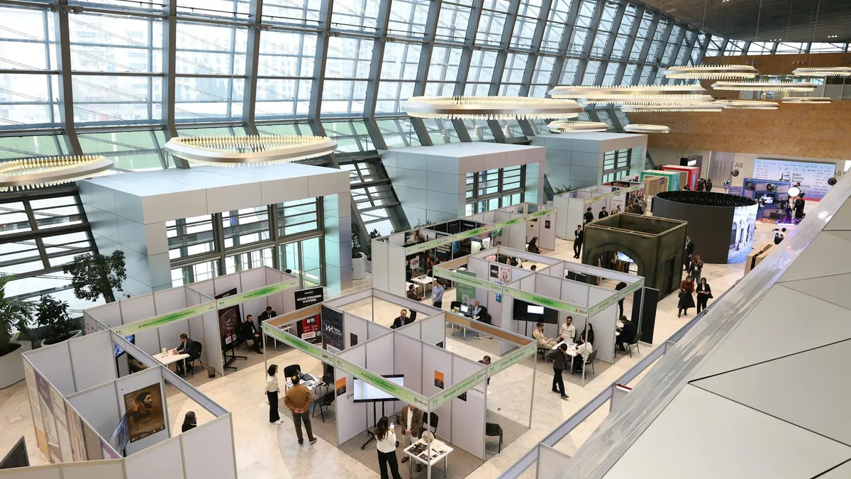 Feria comercial con profesionales haciendo networking entre stands de exposición en un pabellón moderno