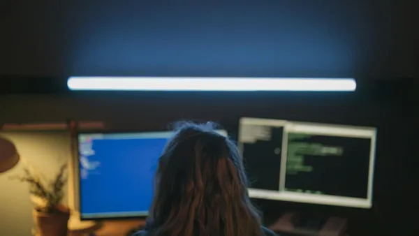 Dos pantallas de ordenador mostrando interfaces de software CRM en una oficina moderna