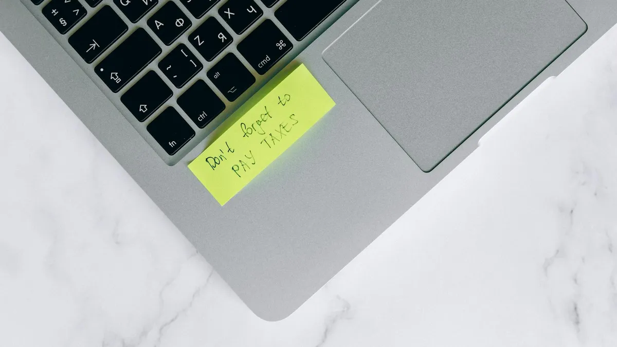 Portátil con nota adhesiva sobre obligaciones fiscales digitales en una oficina
